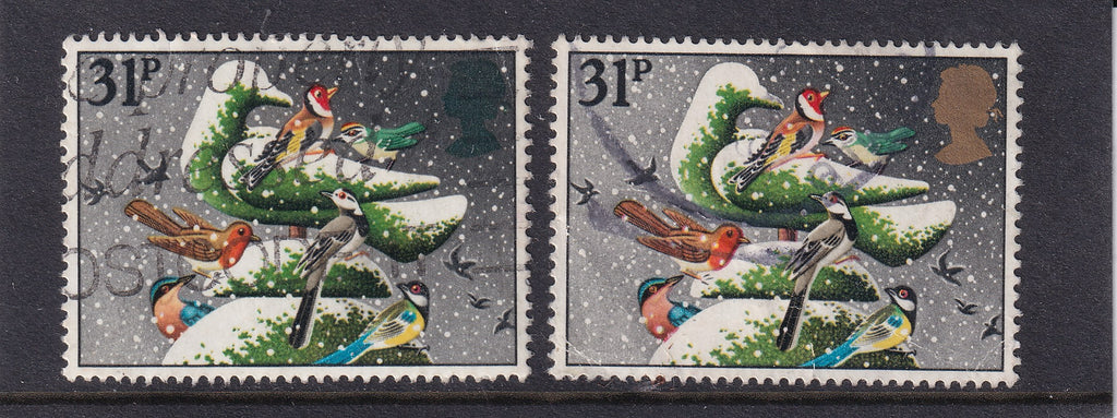 Two used Great Britain 1983 31p Christmas stamps depicting birds on snowy foliage, with a green Queen’s head variety on the left and normal gold head on the right.