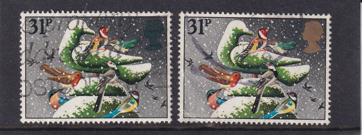 Two used Great Britain 1983 31p Christmas stamps depicting birds on snowy foliage, with a green Queen’s head variety on the left and normal gold head on the right.